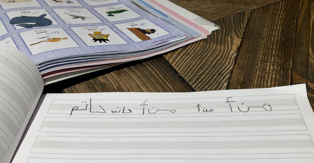 Kuvassa on oppikirja ja vihko, jossa arabiankielistä kirjoitusta.