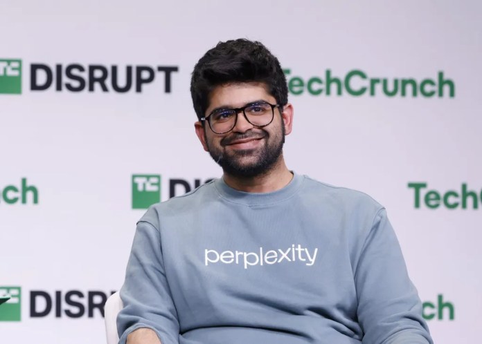 Aravind Srinivas, CEO of Perplexity AI, wearing a sweatshirt with the company logo, speaking at the TechCrunch Disrupt conference about the chrome acquisition.