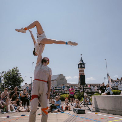 Hands Down Circus Acrobatic performers doing stunt with person flying through air at outdoor SO Festival event with audience