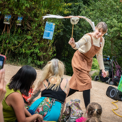 Jane from Barmpot Theatre performing with an owl puppet walking along the front of the audience, who are sat on the floor.
