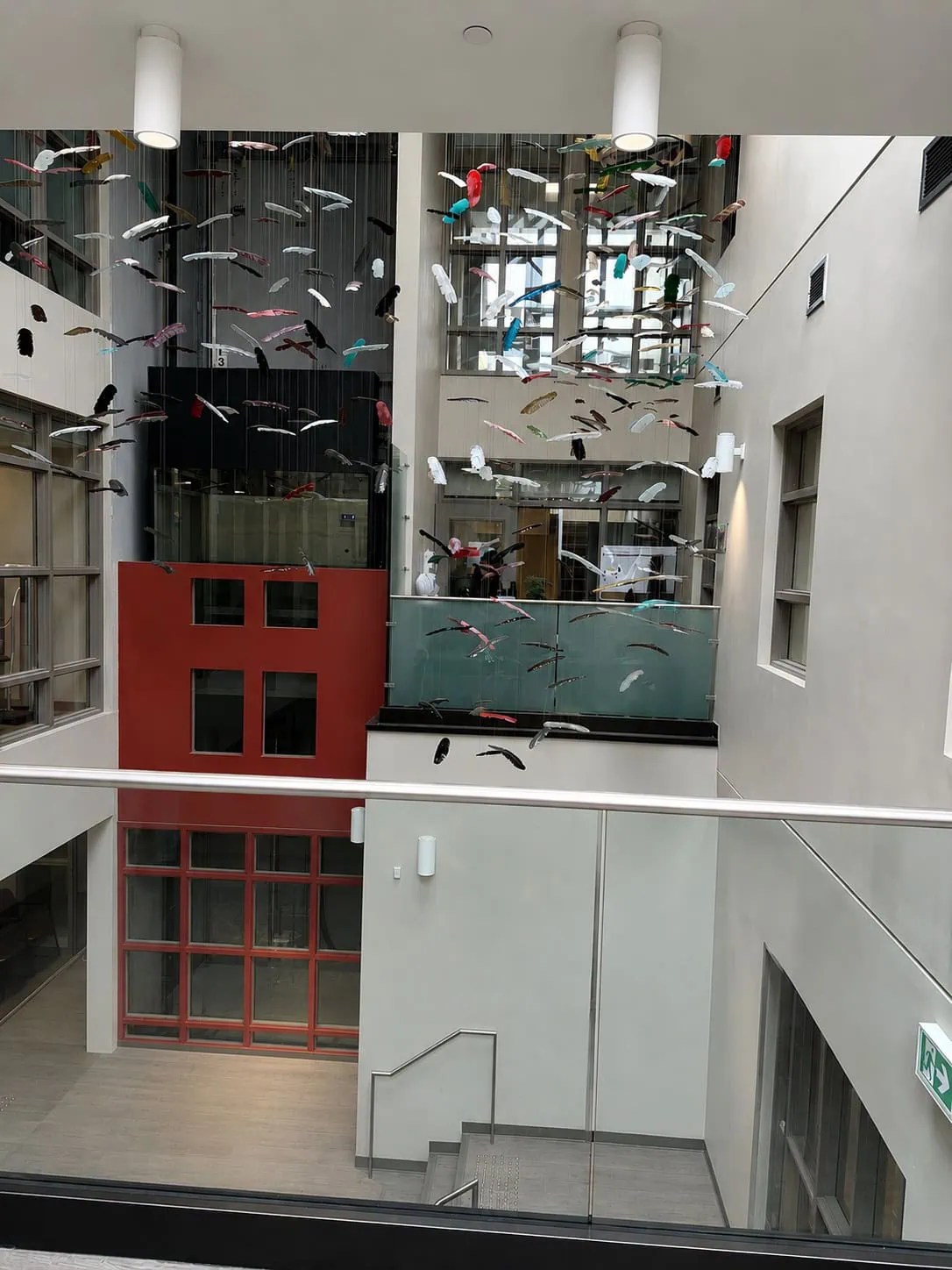 Wide atrium view of Chromatic Canopy showing full drop height of glass feather installation across multi-storey space, SOAHAC London Ontario