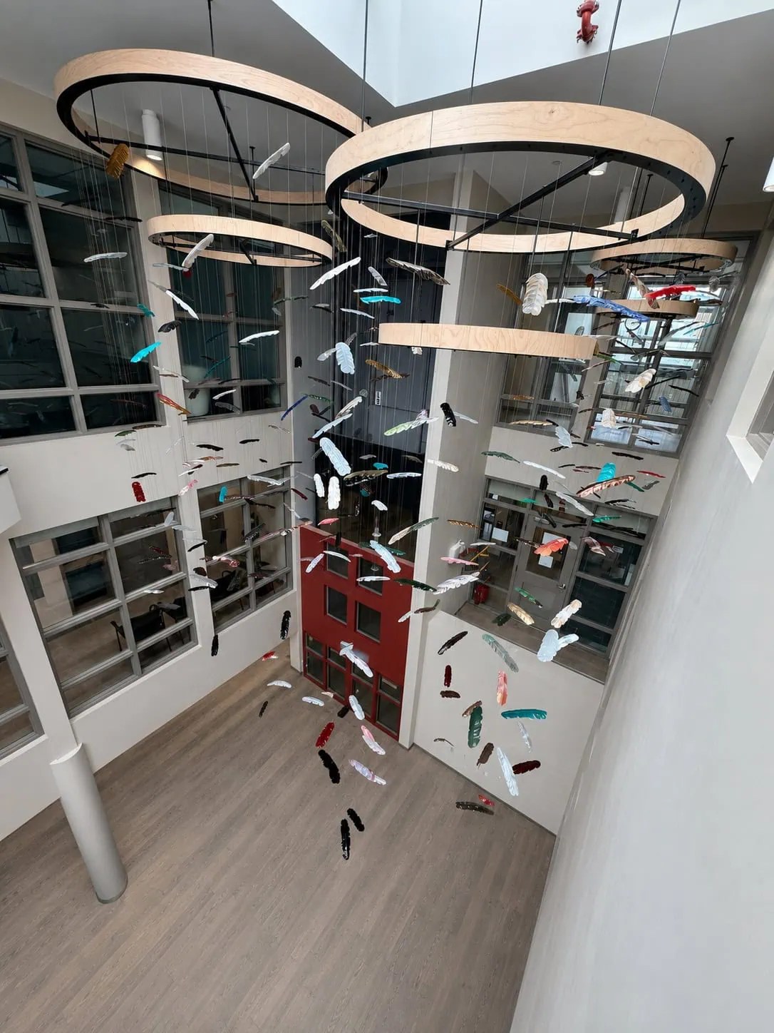 Wide atrium view of Chromatic Canopy showing full drop height of glass feather installation across multi-storey space, SOAHAC London Ontario