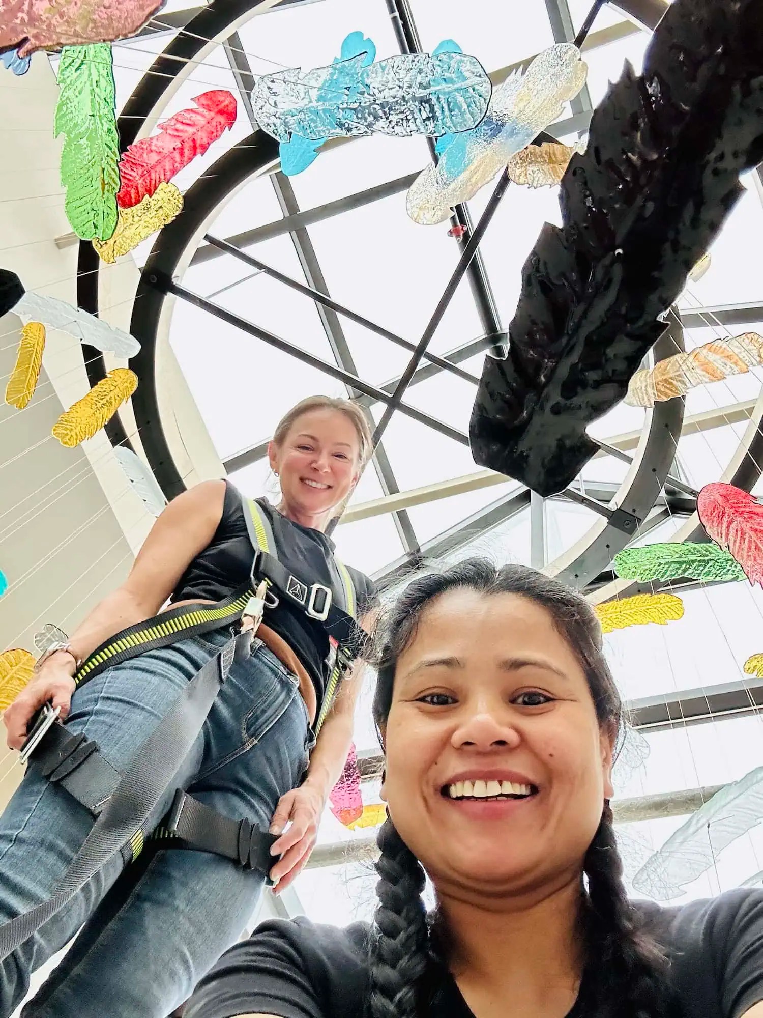 Eva and Amy in safety harnesses during installation of Chromatic Canopy glass feather atrium installation, SOAHAC London Ontario