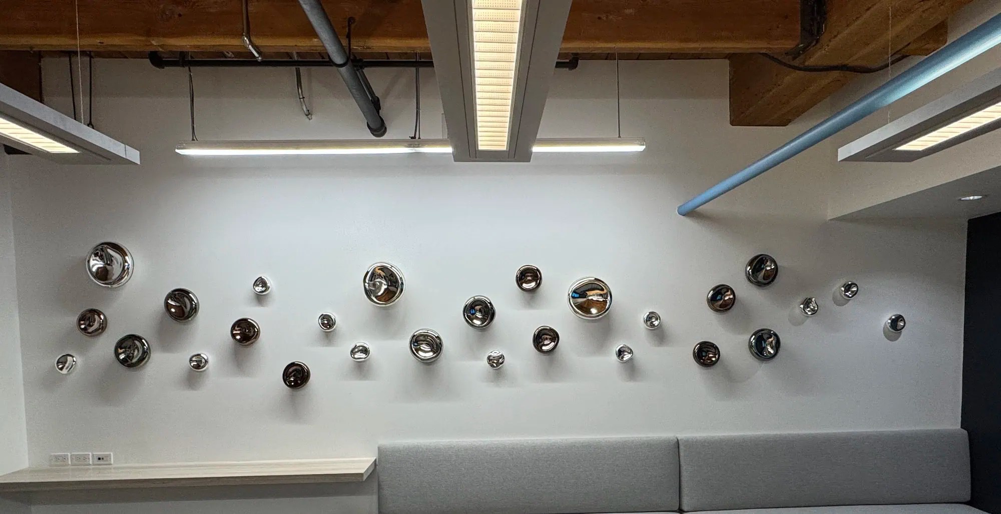 Full horizontal view of Wall Cells installation in mirrored silver, smokey topaz and grey along white wall, SGH Design Partners Toronto boardroom