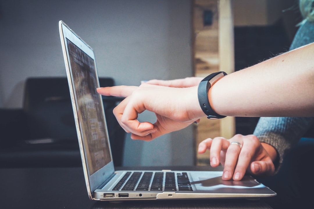 People are pointing at a laptop screen.