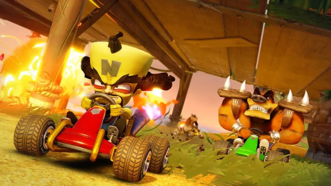 La imagen muestra una escena vibrante y emocionante del videojuego "Crash Team Racing Nitro Fueled", un título icónico en el género de carreras de karts. En el centro, dos personajes emblemáticos compiten ferozmente, cada uno conduciendo un kart personalizado que refleja sus características únicas. La acción es intensa, con explosiones y detalles dinámicos en el entorno, capturando la esencia adrenalínica de "Crash Team Racing Nitro Fueled". Los colores brillantes y las expresiones decididas de los personajes resaltan la naturaleza competitiva y divertida del juego, ofreciendo a los jugadores una experiencia visualmente atractiva y llena de energía.