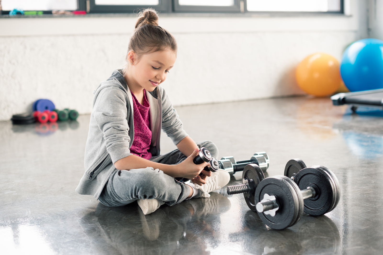 An image of a young girls playing with dumbbells - strength training for children starts with fun.