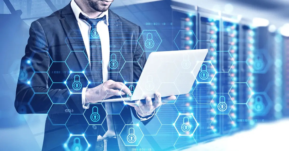 Man working on laptop in data center.