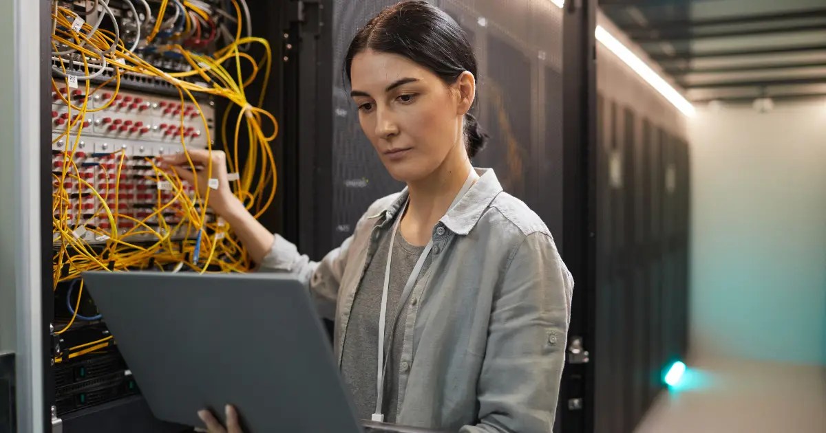 Female Network Technician Inspecting Servers in Data Center