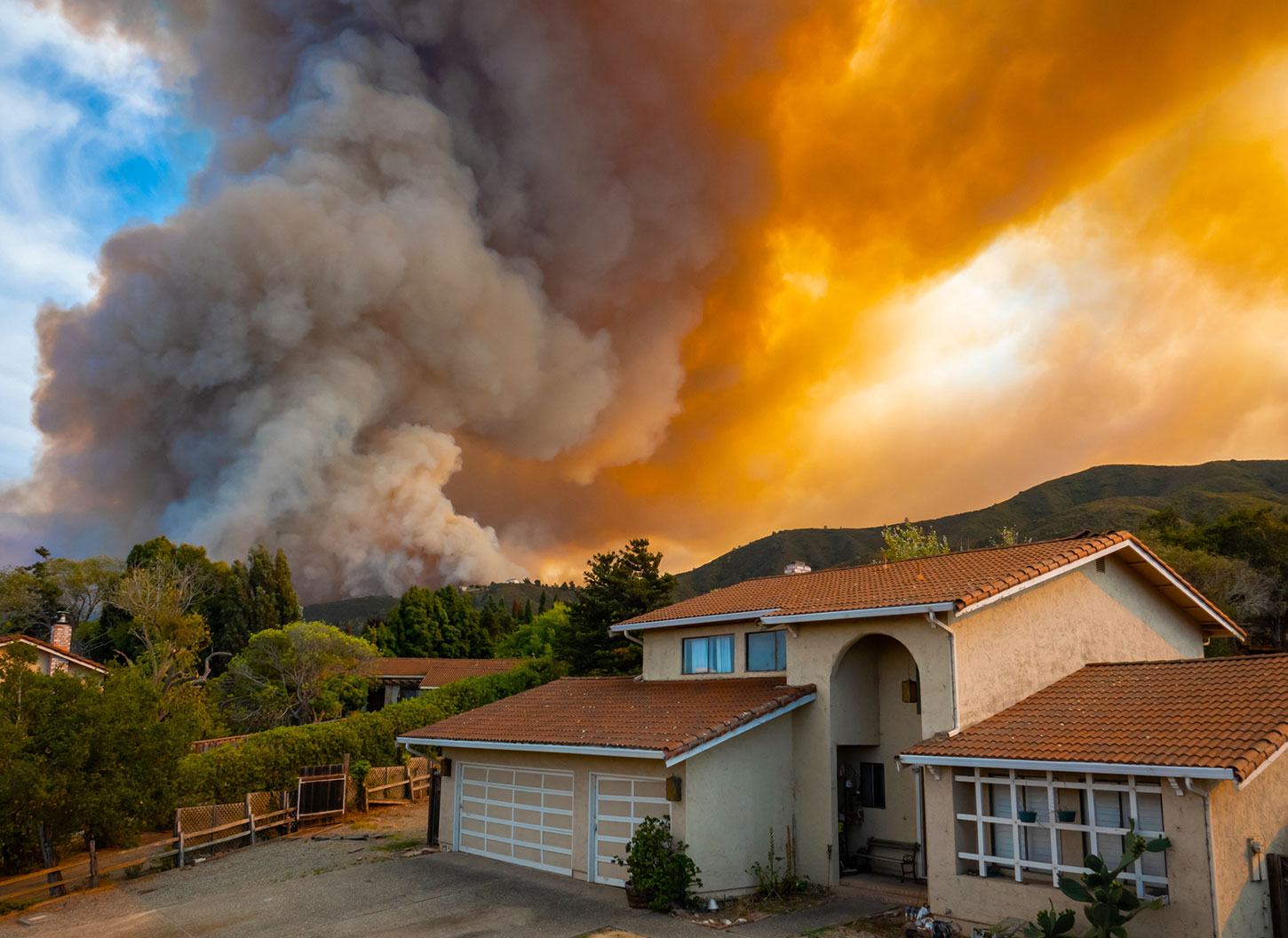 Suburban house with wildfire on horizon