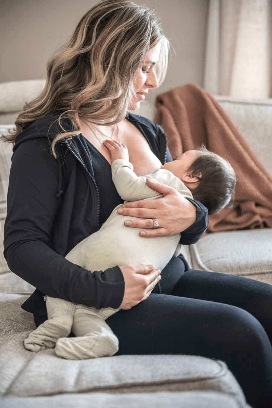 Mom looks at baby latching on breast.