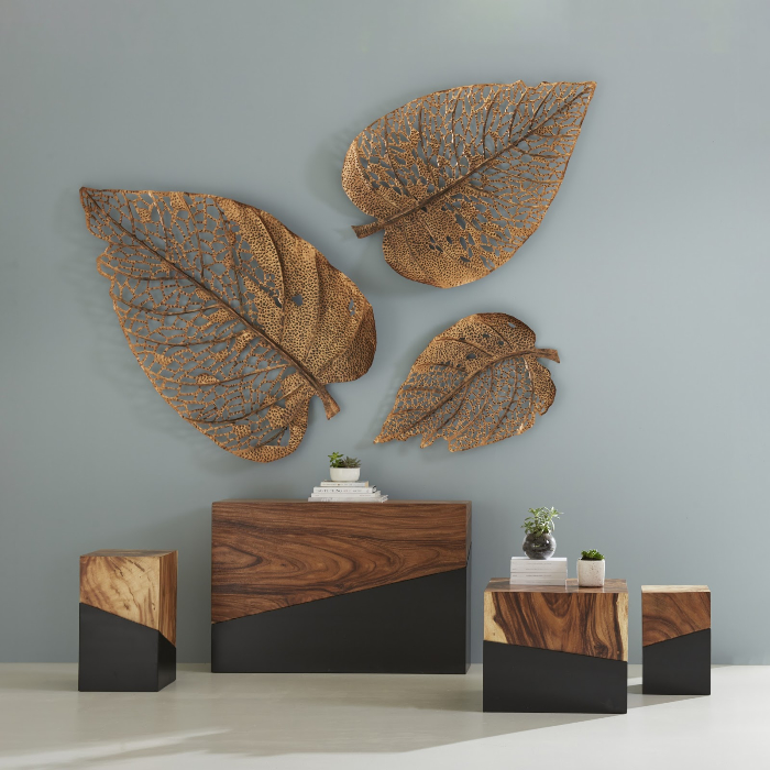 Golden metal leaf wall decor above modern wooden furniture.