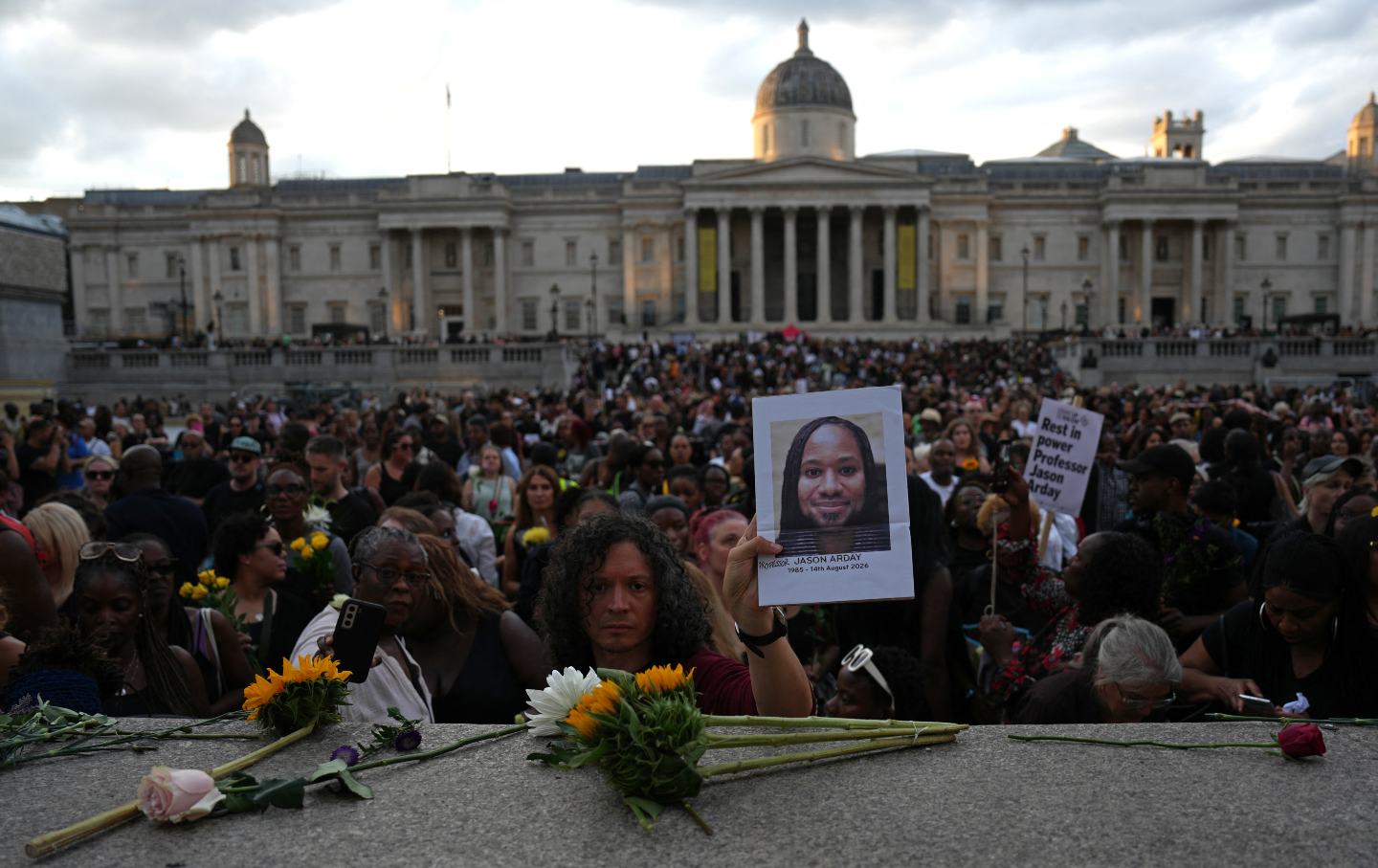 Supporters leave flowers and photographs after taking part in a vigil for late Cambridge professor Jason Arday in Trafalgar Square in central London on August 17, 2026, following his death at age 41 on August 14.