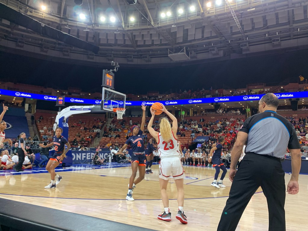 A Georgia player holds the ball above her head as an Auburn player closes out.