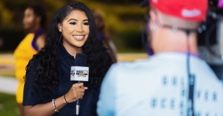 Tykera Careter is pictured wearing a black polo top and holding a microphone that has "HBCU Sports Go" on it.