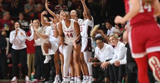 Pac-12 action: Kiki Iriafen (44) smiles and claps for her Stanford teammates from the bench, alongside fellow Stanford players and coaches.