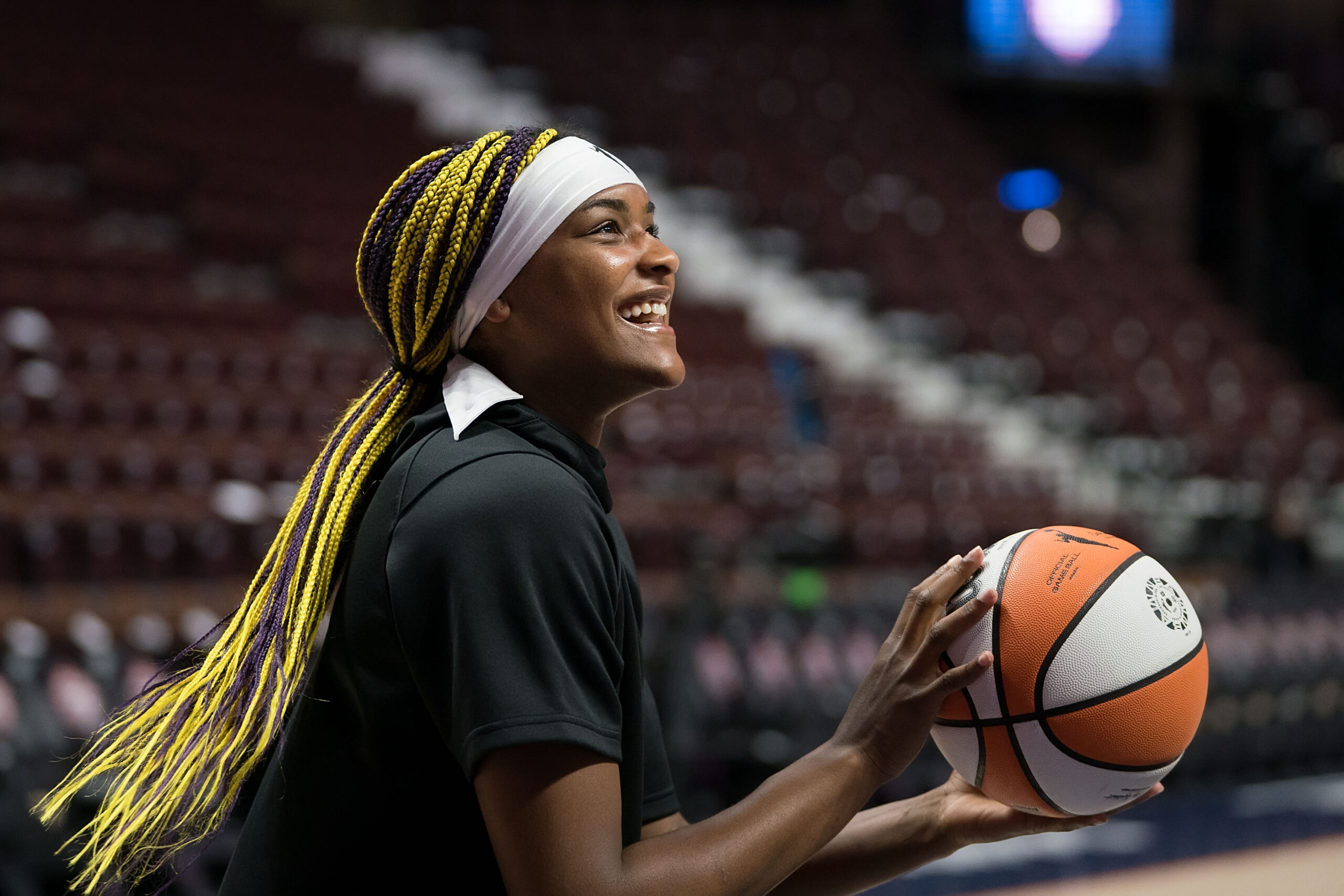 Washington Mystics forward Aaliyah Edwards is shown in profile, smiling broadly as she prepares to take a shot in warmups.