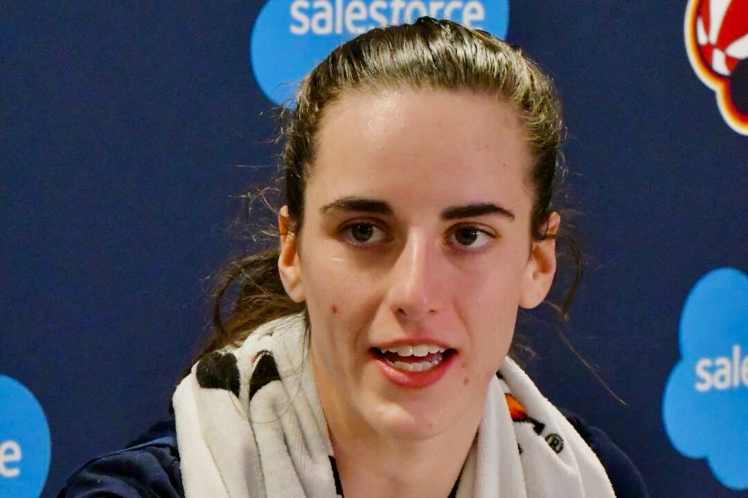 Indiana Fever guard Caitlin Clark is pictured with a towel draped over her shoulders while seated in a press conference