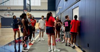 Washington Mystics head coach Eric Thibault draws up a play on a permanent whiteboard at the team's practice facility as his players look on.