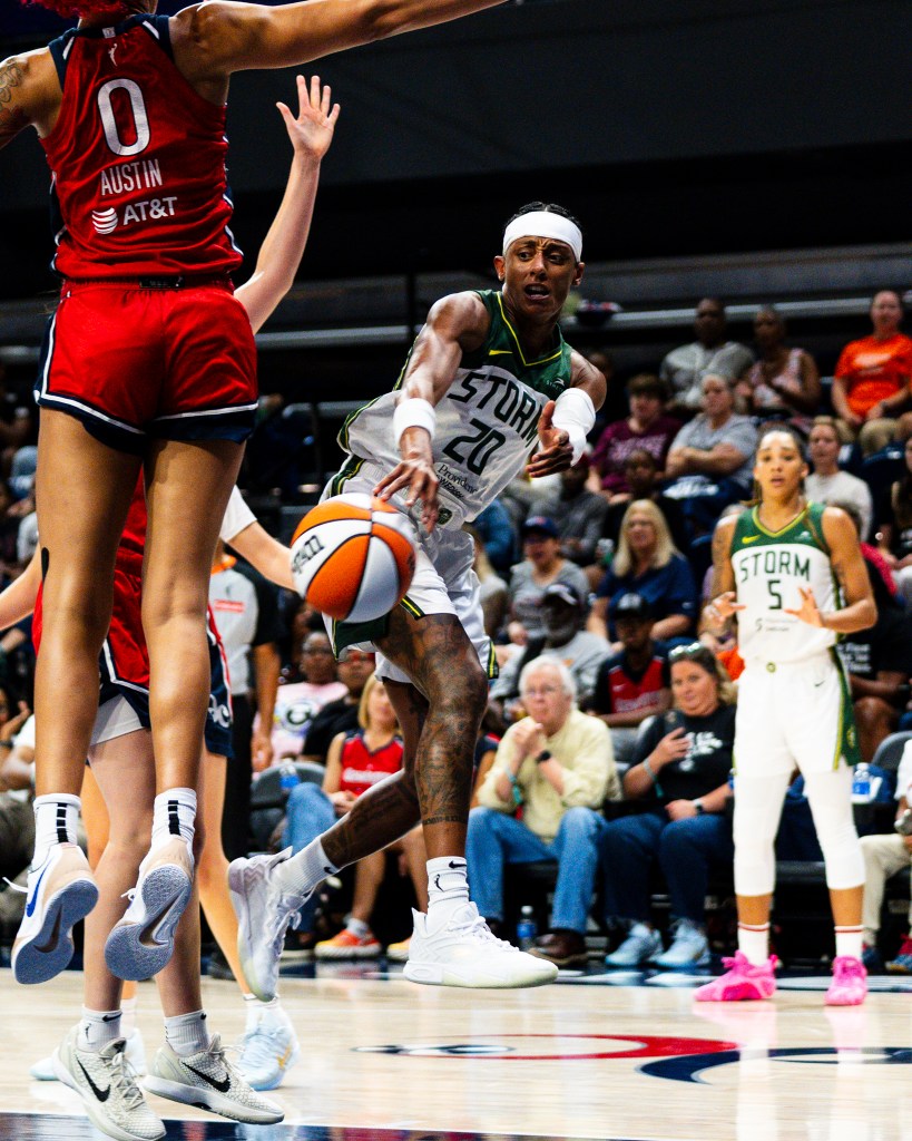 Brittney Sykes throws a bounce pass between Washington Mystics defenders from mid-air as she is falling away.