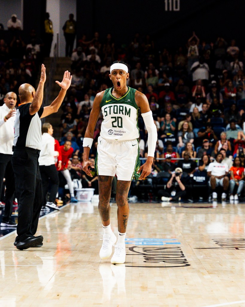 Brittney Sykes flexes and lets out a yell as she walks back to her bench and the referee signals the made three-point shot behind her.