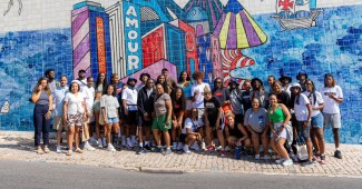 Howard women's basketball is standing in front of a tiled mural wall in Lisbon, Portugal. which is a strong symbol tied to Portugal’s maritime history.