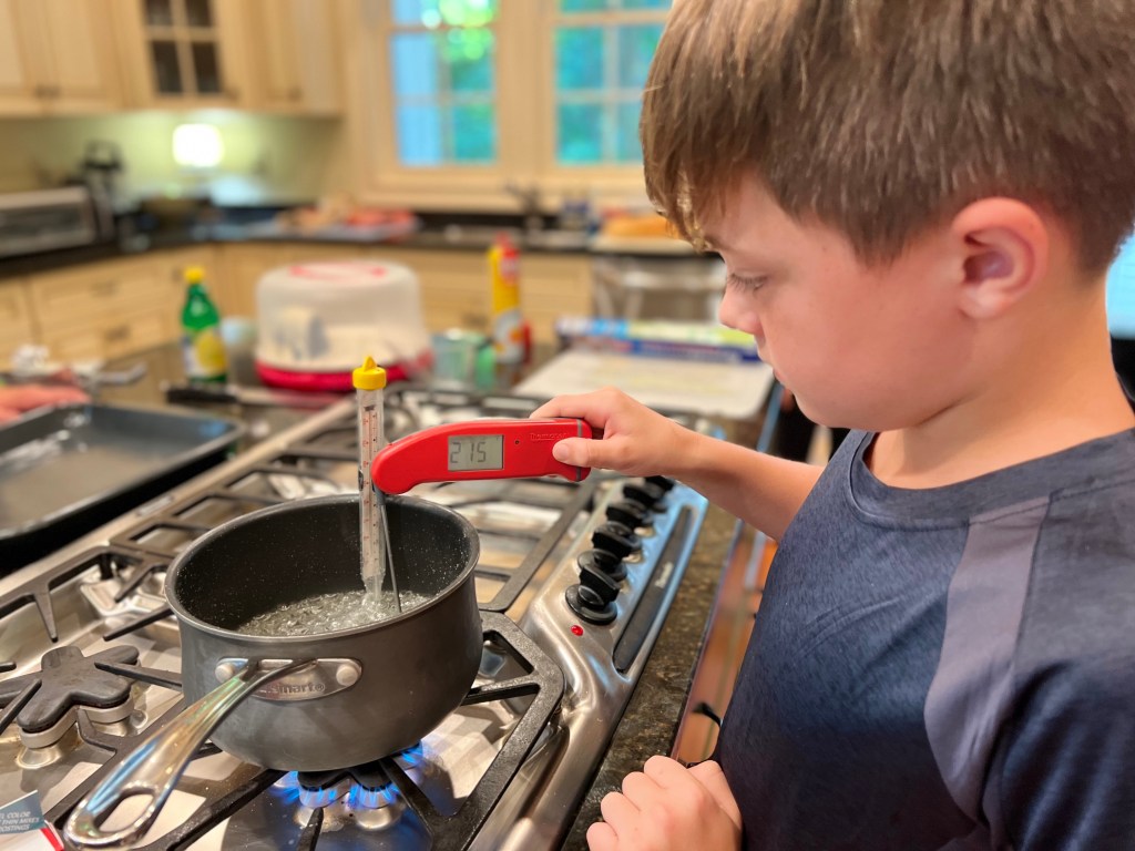 measuring the temperature for the sugar glass for the Ironman Cake. My son working with adult supervision