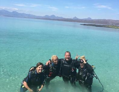 Happy Divers pose for a picture in the shallow clear waters of Coronado Island while taking an Introduction to diving course