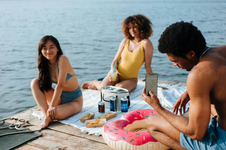 a man in blue shorts taking picture of a woman in blue bikini