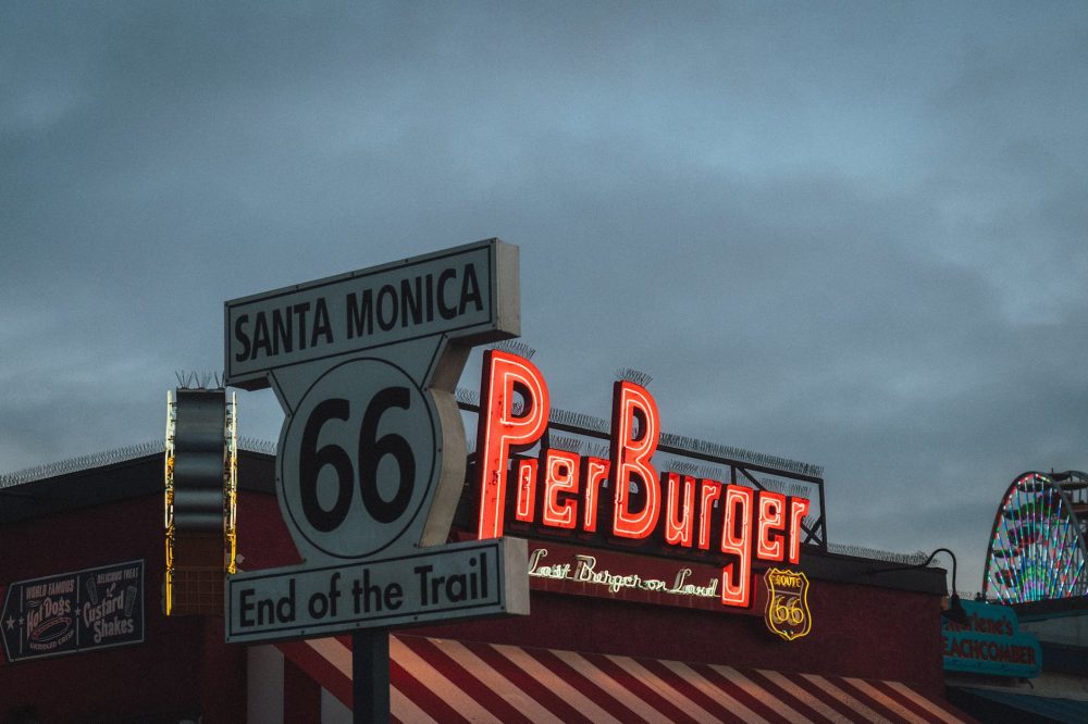 l'insegna di un ristorante sul Santa Monica pier e di fronte il cartello che indica il termine della Route 66