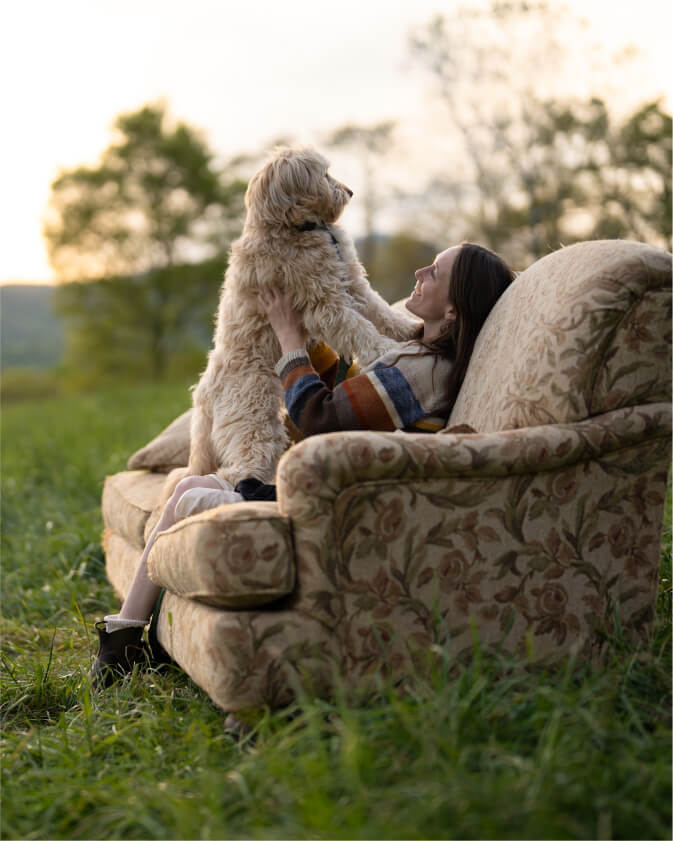 A student sits with their dog on a couch outside.