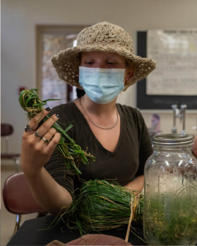 A student wearing a surgical mask holds a bundle of fibers.