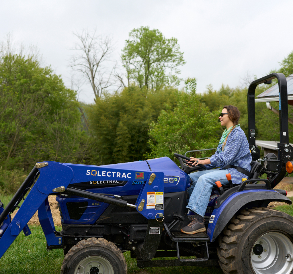 A student drives a blue electric tractor.