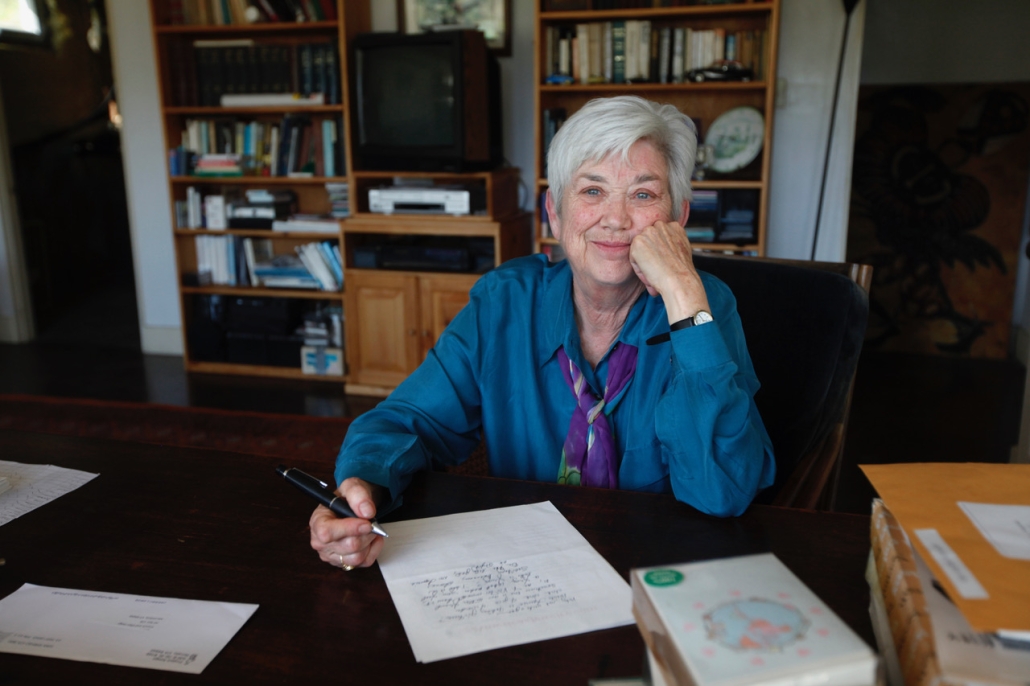 Ellen Bryant Voigt, creator of warren wilson college's Master of fine arts program for writers, sits at a table, pen in hand, writing.