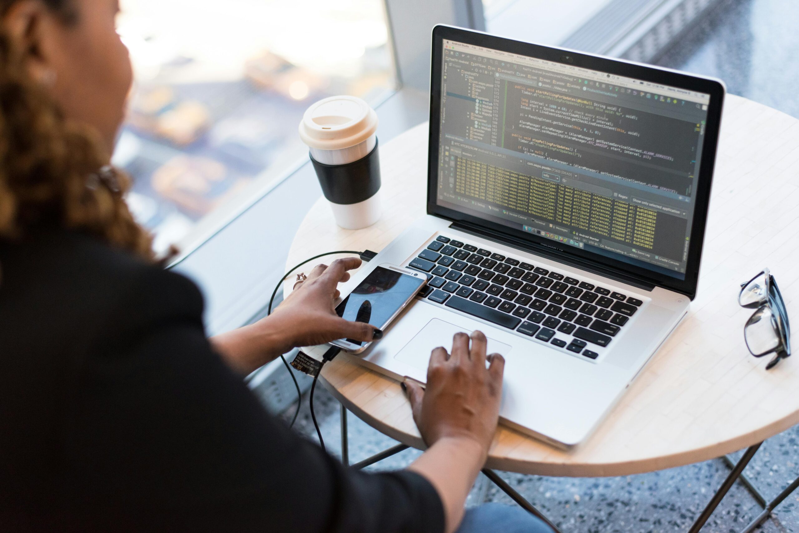 Female professional working on a laptop at a desk with a coffee cup.