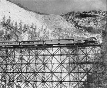 Special-effects men produced realistic scene of train crossing trestle. Hidden in the trestle are cables to pull it down.