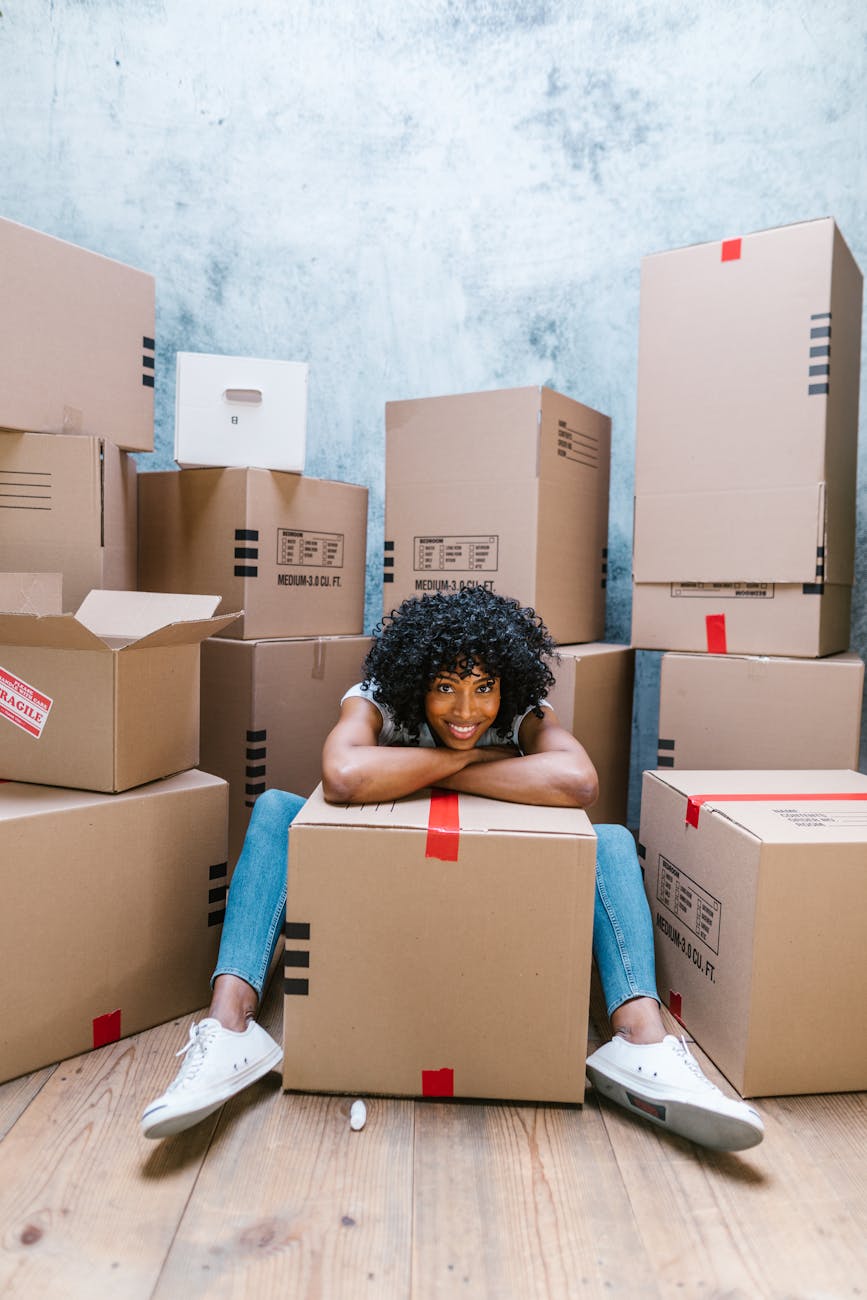 woman in blue denim jeans sitting on brown cardboard boxes