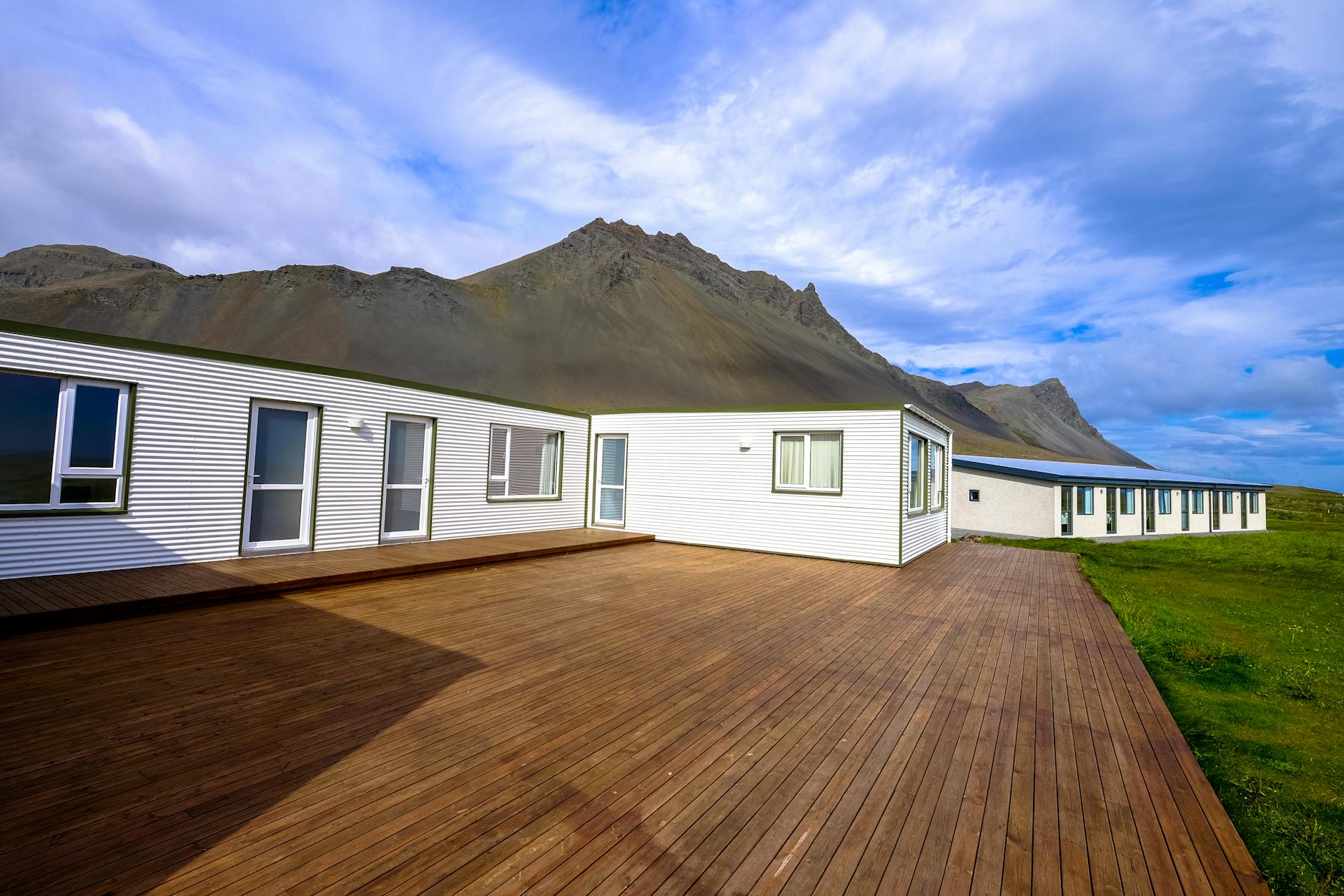 mountain across houses on green grass field under clear blue sky