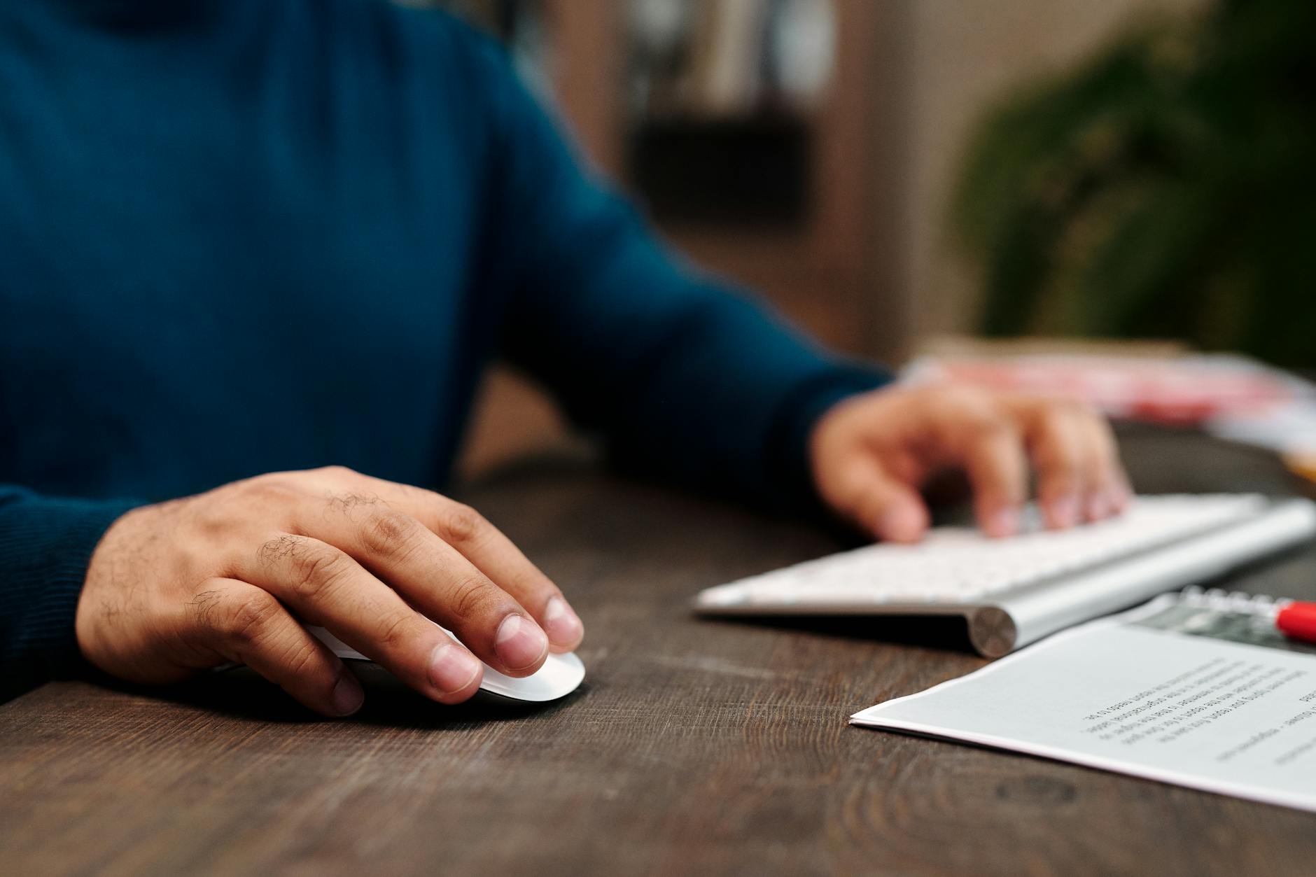 close up of man holding his hand on a wireless computer mouse and keyboard
