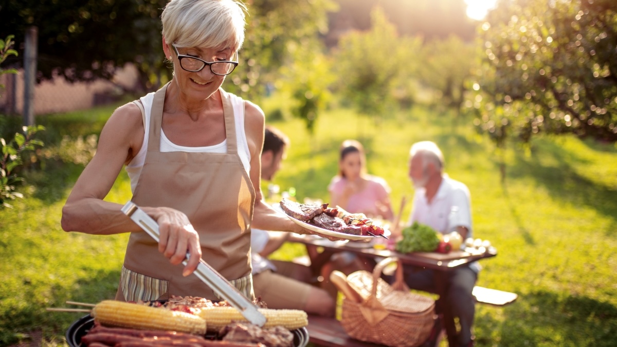 A woman grilling outdoors with friends after learning how to reverse aging by reducing AGEs