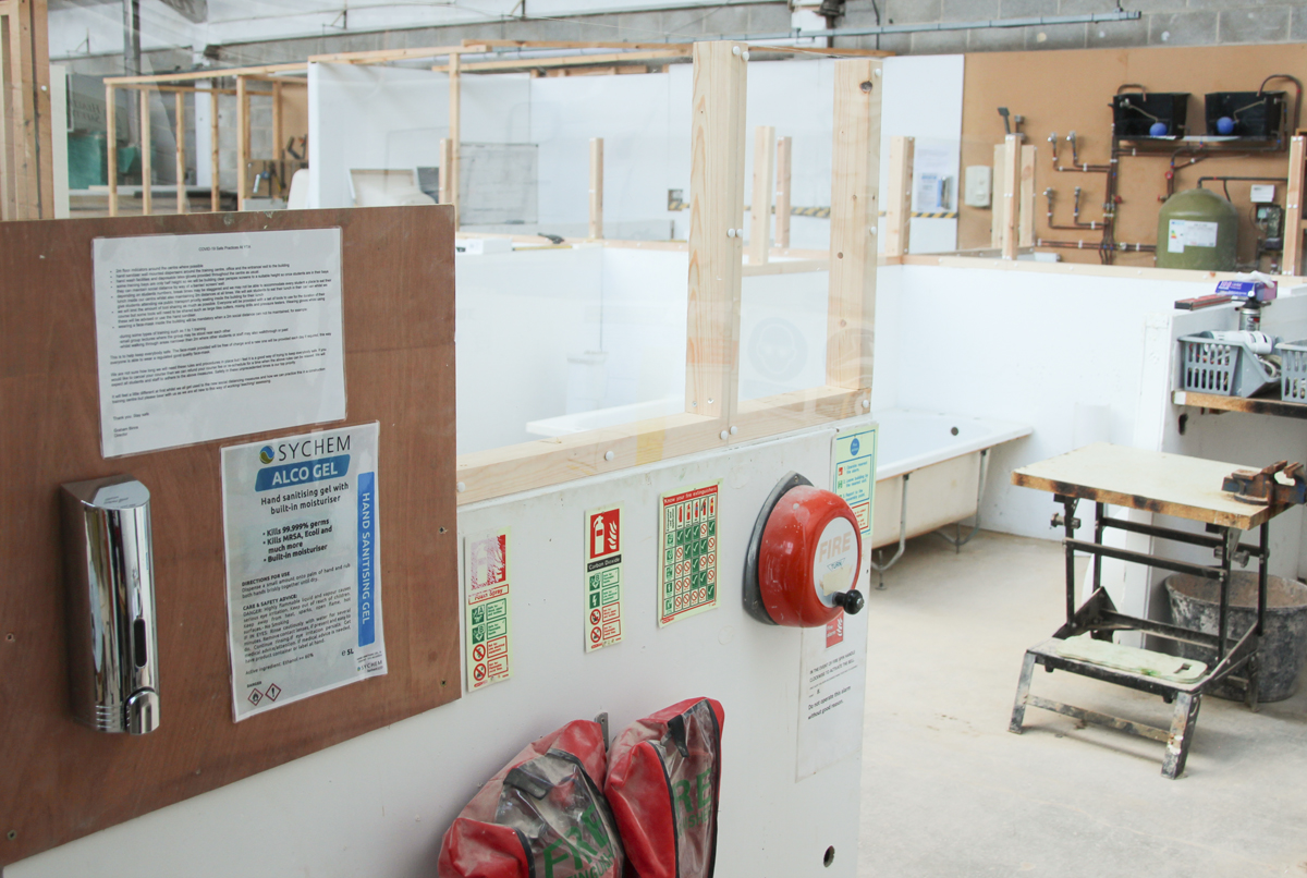 Hand sanitiser and perspex between plumbing training bays