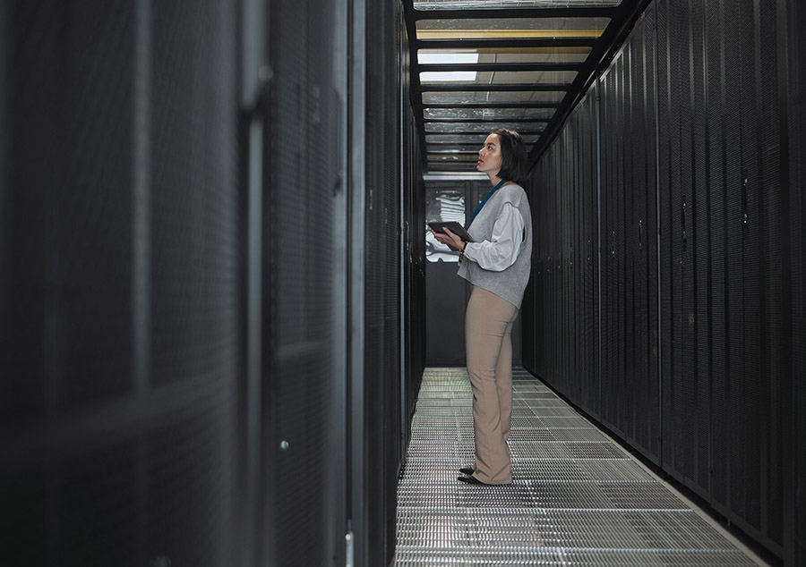 IT technician in a server room with tablet. IT technician in a server room with tablet.