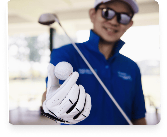 Golfer smiling and holding up a golf ball during a lesson