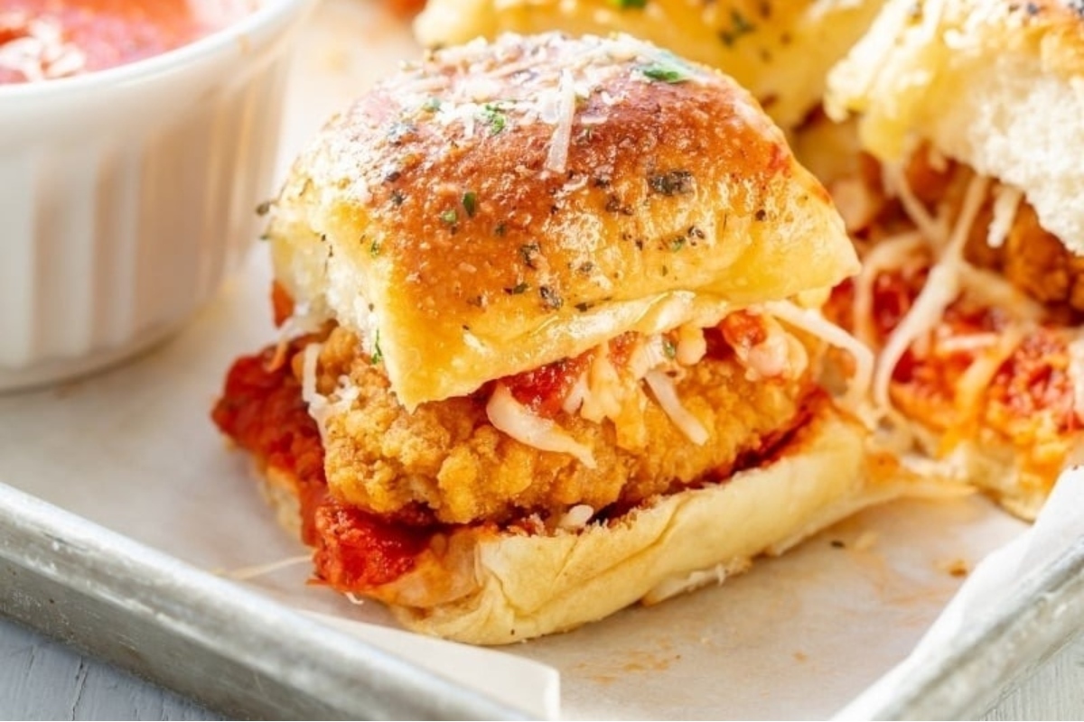 Chicken parmigiana sliders, the perfect bite-sized variation of the classic dish. Prepared on a tray and served with a delectable sauce.