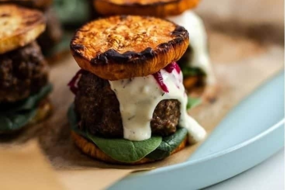 A plate of slider burgers with a sauce on top.