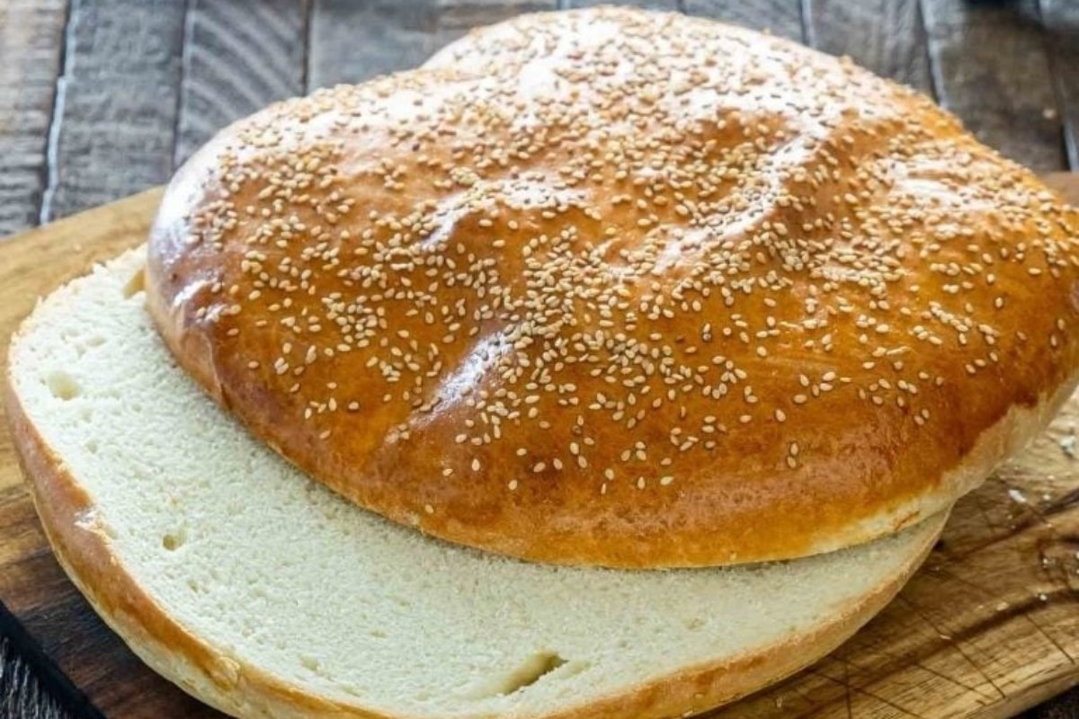 A loaf of bread with sesame seeds on a wooden cutting board, inspired by diverse bread recipes.