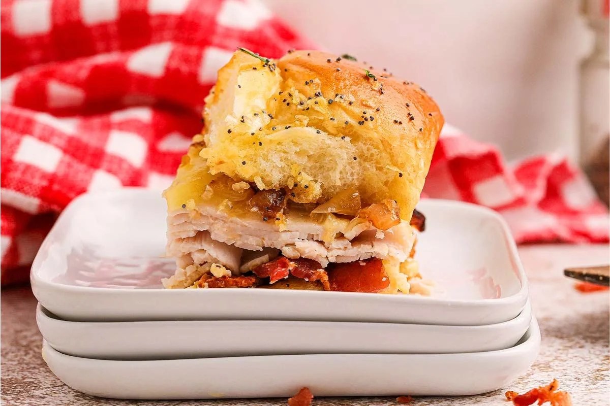 Turkey and bacon sliders on a plate with ketchup and mustard.