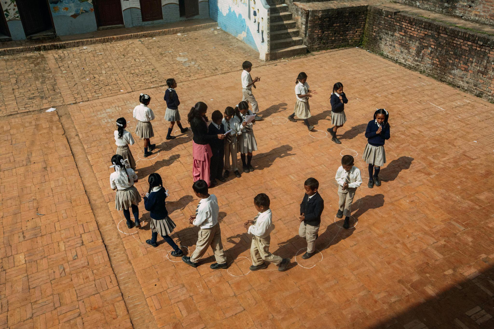 A photo from above looking down on children in a circle with an adult in the middle.