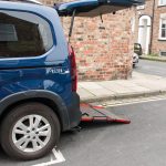 A wheelchair adapted vehicle has it's rear open and a ramp down