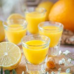 Homemade Ginger and Citrus Immunity Shots on the table alongside with citrus.